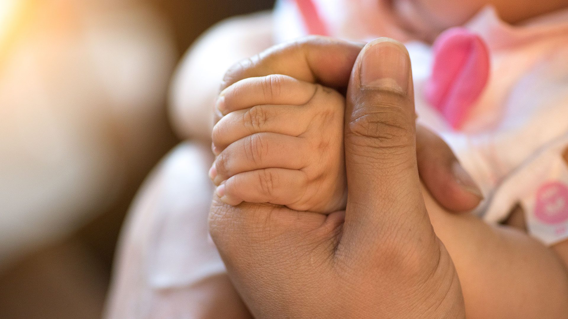 woman holding baby's hand